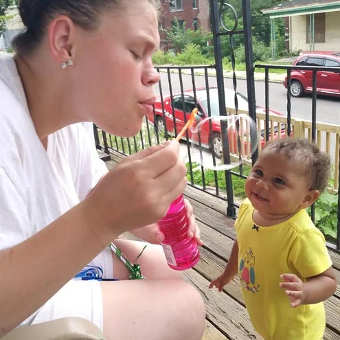 Parent blowing bubbles outside to entertain baby in the HealthyINFANT program